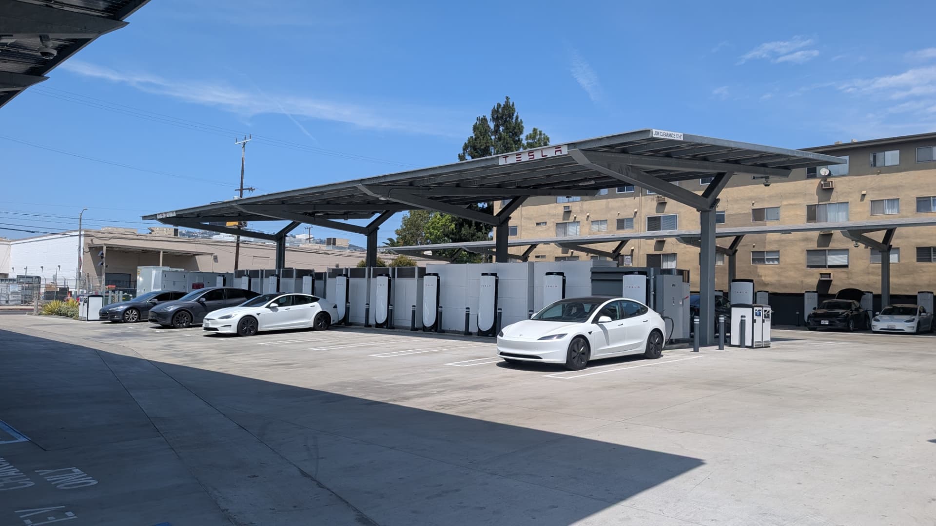 Tesla Supercharger stalls under a solar canopy at a commercial property